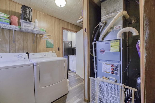 1650 S Fort Ave, Springfield, MO 65807 - laundry room featuring washer and clothes dryer, heating unit, wooden walls, and light wood finished floors