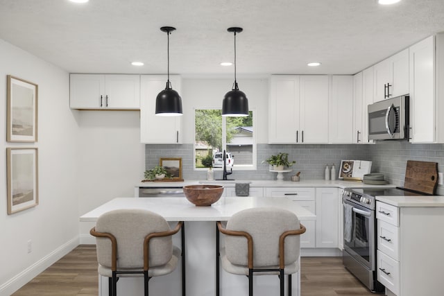 4959 S Mccann Ave, Springfield, MO 65804 - kitchen featuring appliances with stainless steel finishes, a breakfast bar, white cabinetry, and recessed lighting