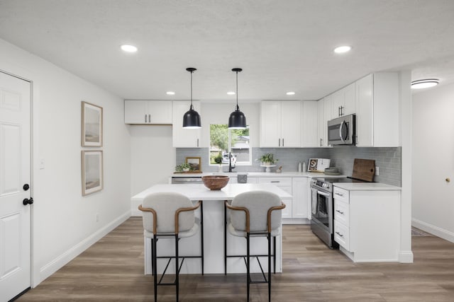 4959 S Mccann Ave, Springfield, MO 65804 - kitchen with appliances with stainless steel finishes, a breakfast bar, backsplash, light countertops, and recessed lighting
