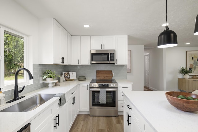 4959 S Mccann Ave, Springfield, MO 65804 - kitchen featuring appliances with stainless steel finishes, light wood-style floors, backsplash, white cabinets, and pendant lighting