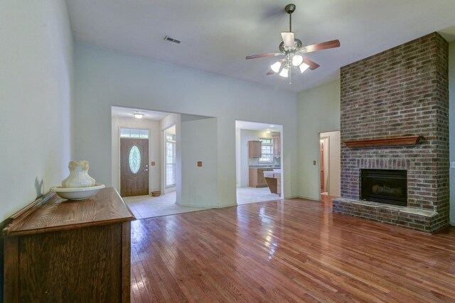 613 Crossing Dr, Branson West, MO 65737 - unfurnished living room with wood finished floors, healthy amount of natural light, a ceiling fan, and a brick fireplace