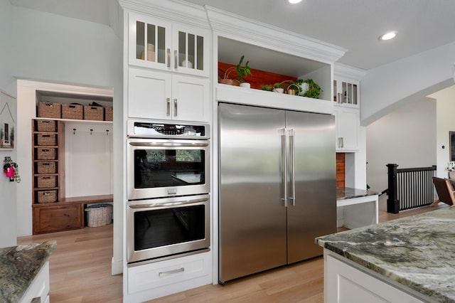 1373 E River Oak Dr, Springfield, MO 65803 - kitchen featuring appliances with stainless steel finishes, arched walkways, dark stone counters, light wood-type flooring, and recessed lighting