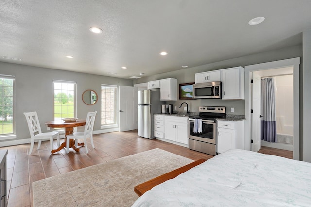 1373 E River Oak Dr, Springfield, MO 65803 - kitchen featuring appliances with stainless steel finishes, white cabinets, wood finished floors, recessed lighting, and stone countertops