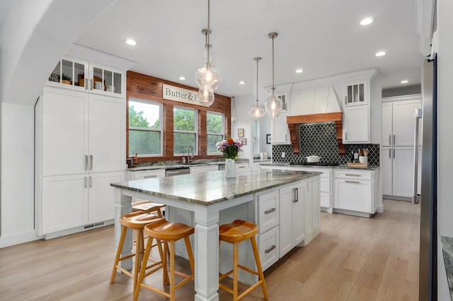 1373 E River Oak Dr, Springfield, MO 65803 - kitchen featuring custom exhaust hood, a center island, decorative backsplash, light wood-style floors, and white cabinets