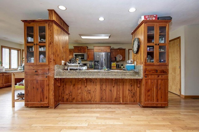 637 State Highway Kk, Cedar Creek, MO 65627 - kitchen with stainless steel appliances, light wood-style flooring, glass insert cabinets, brown cabinets, and a peninsula