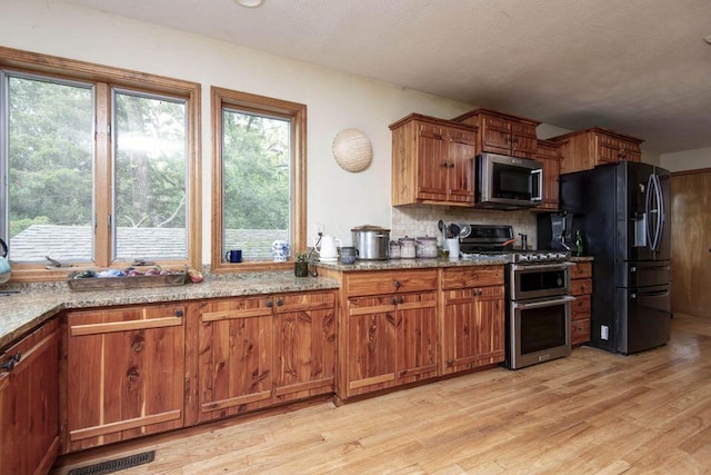 637 State Highway Kk, Cedar Creek, MO 65627 - kitchen featuring stainless steel appliances, light wood finished floors, brown cabinetry, backsplash, and light stone countertops