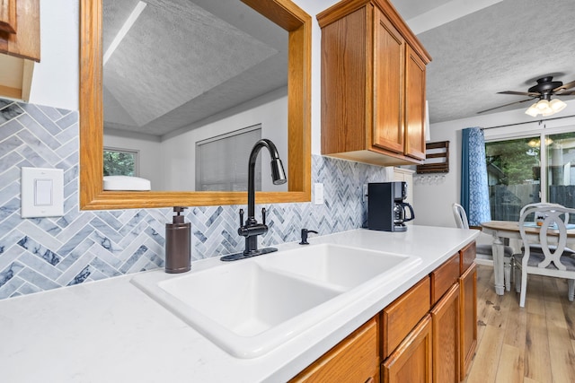 4105 S Oak Ave, Springfield, MO 65804 - kitchen featuring a textured ceiling, brown cabinetry, light wood finished floors, light countertops, and backsplash