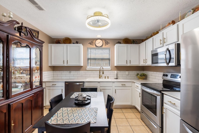 128 Knowledge Ave Unit 2, Branson, MO 65616 - kitchen with stainless steel appliances, light countertops, decorative backsplash, white cabinetry, and a textured ceiling