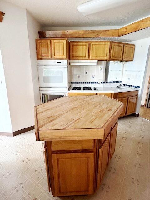 9387 State Highway 13, Kimberling City, MO 65686 - kitchen with white double oven, stainless steel gas cooktop, light flooring, and brown cabinetry