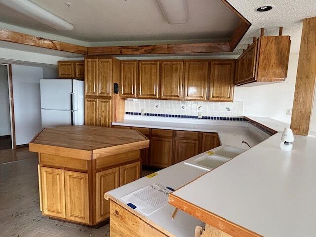 9387 State Highway 13, Kimberling City, MO 65686 - kitchen with freestanding refrigerator, brown cabinetry, and decorative backsplash