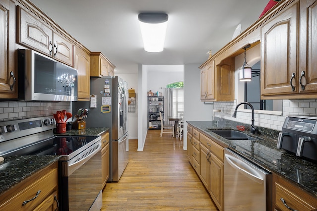 103 Fawn Trl, Neosho, MO 64850 - kitchen with appliances with stainless steel finishes, light wood-style flooring, tasteful backsplash, dark stone counters, and pendant lighting