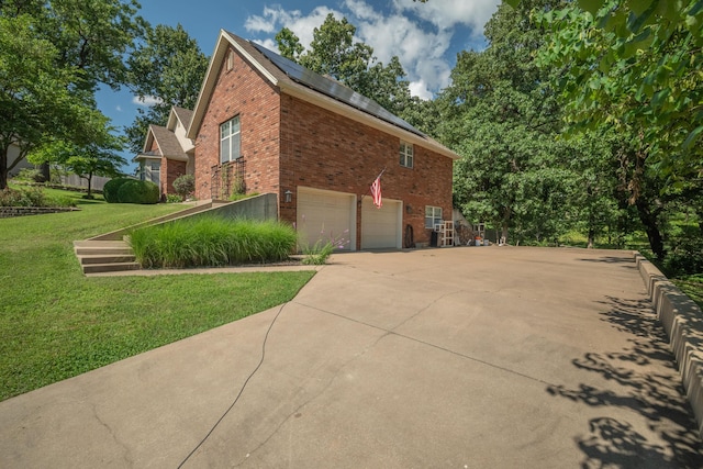 103 Fawn Trl, Neosho, MO 64850 - view of side of property featuring brick siding, a garage, solar panels, a lawn, and concrete driveway