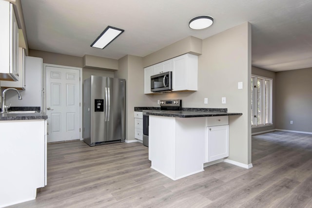 3229 W Hanover St, Springfield, MO 65807 - kitchen with stainless steel appliances, light wood-style floors, dark countertops, and white cabinetry