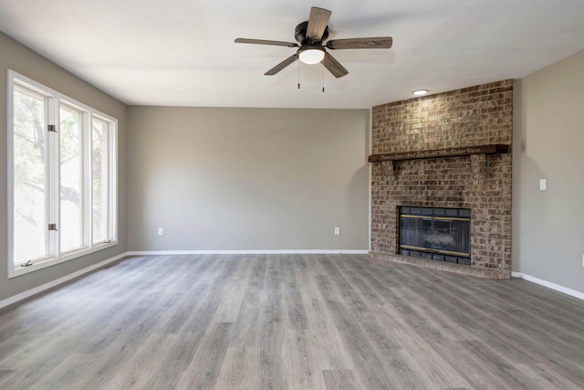 3229 W Hanover St, Springfield, MO 65807 - unfurnished living room with wood finished floors, ceiling fan, and a brick fireplace