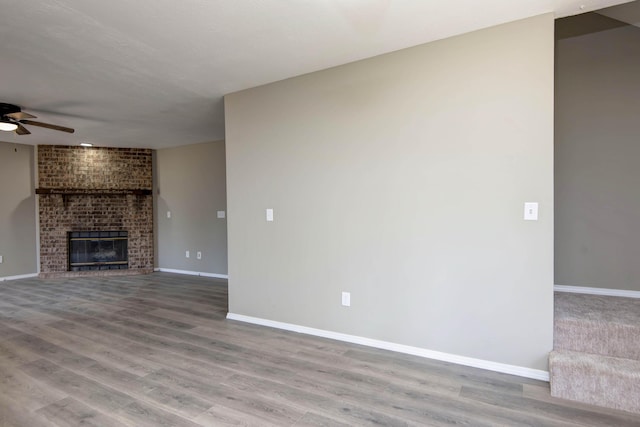 3229 W Hanover St, Springfield, MO 65807 - unfurnished living room featuring a ceiling fan, wood finished floors, and a brick fireplace