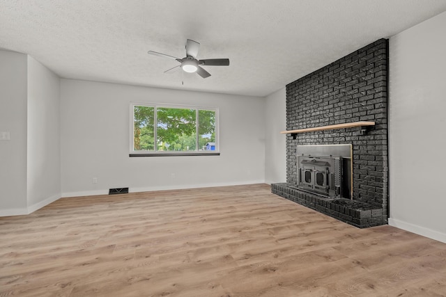 302 W Howard Ave, Billings, MO 65610 - unfurnished living room with ceiling fan, a brick fireplace, wood finished floors, and a textured ceiling