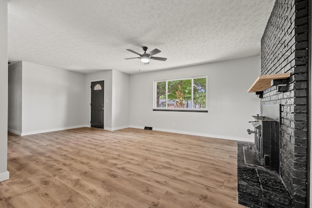 302 W Howard Ave, Billings, MO 65610 - unfurnished living room with a ceiling fan, a fireplace, a textured ceiling, and light wood-style floors