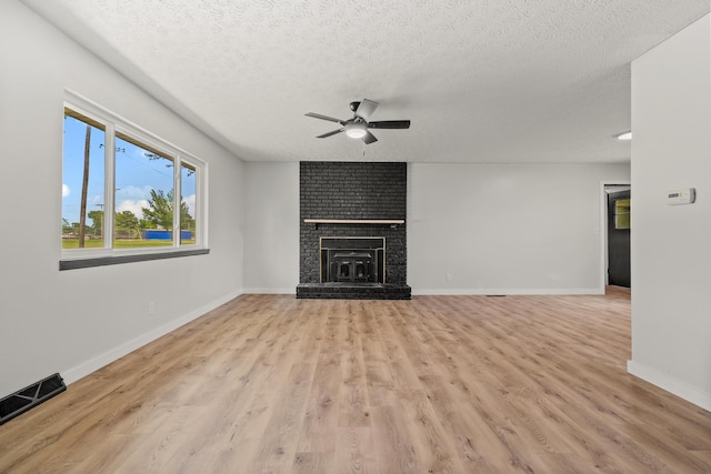 302 W Howard Ave, Billings, MO 65610 - unfurnished living room featuring a ceiling fan, light wood-style flooring, a textured ceiling, and a fireplace