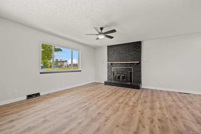 302 W Howard Ave, Billings, MO 65610 - unfurnished living room featuring ceiling fan, a textured ceiling, wood finished floors, and a fireplace