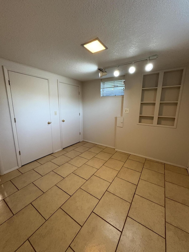 311 Crestwood Dr, Neosho, MO 64850 - spare room with a textured ceiling, track lighting, light tile patterned floors, and built in shelves