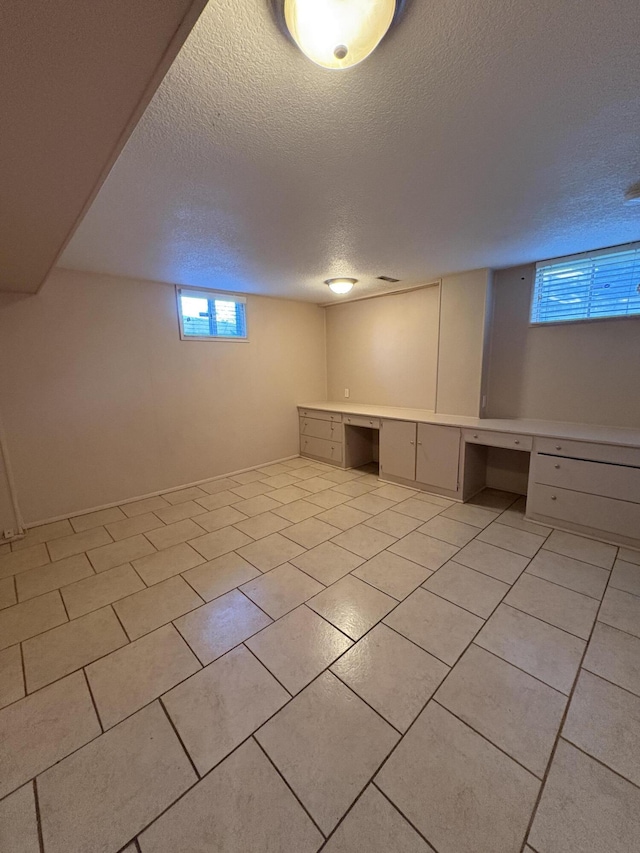 311 Crestwood Dr, Neosho, MO 64850 - below grade area featuring a textured ceiling, light tile patterned floors, and a desk