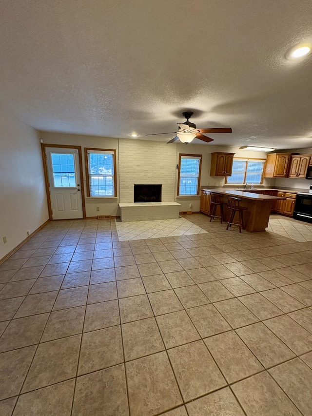 311 Crestwood Dr, Neosho, MO 64850 - living area with a textured ceiling, light tile patterned floors, a brick fireplace, a ceiling fan, and recessed lighting
