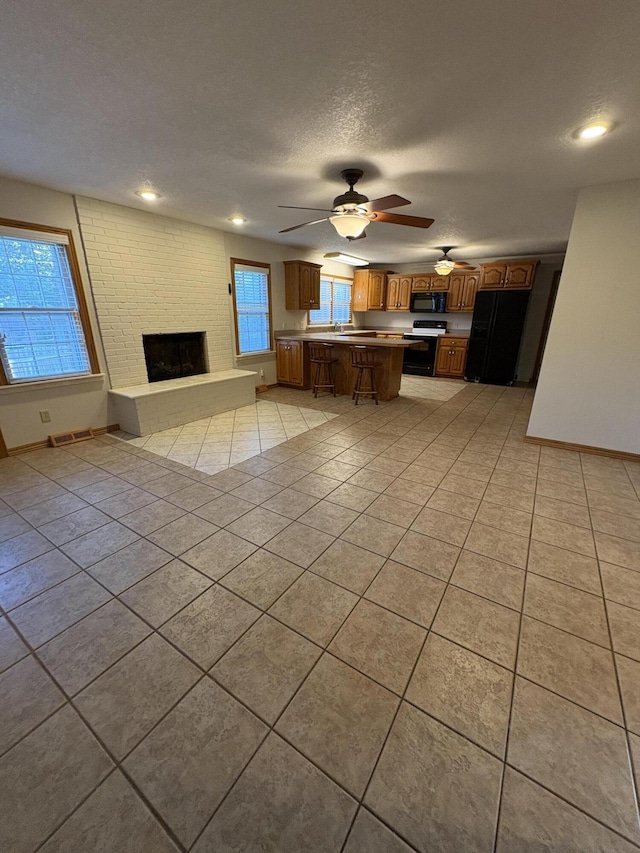 311 Crestwood Dr, Neosho, MO 64850 - kitchen featuring black appliances, open floor plan, light tile patterned floors, brown cabinets, and a fireplace