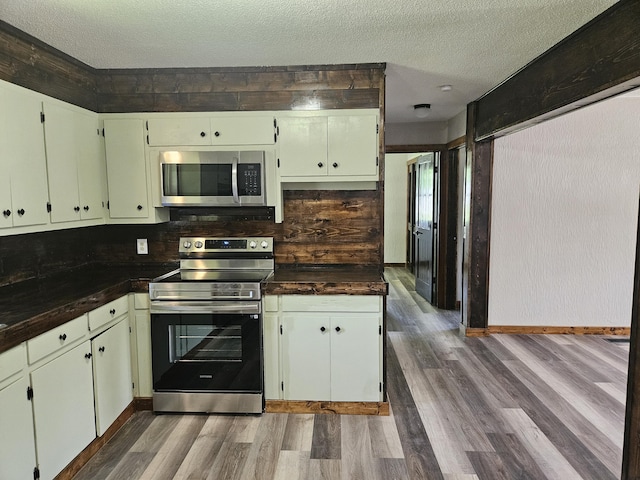 401 Walnut St, Ava, MO 65608 - kitchen featuring stainless steel appliances, wood finished floors, dark countertops, and a textured ceiling