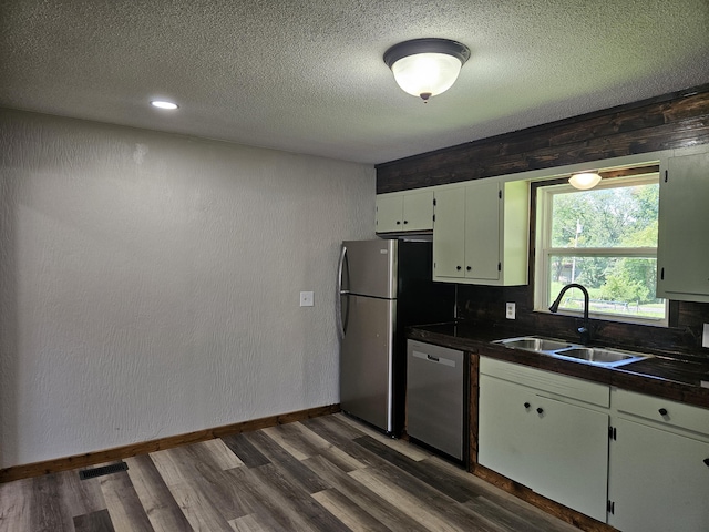 401 Walnut St, Ava, MO 65608 - kitchen featuring appliances with stainless steel finishes, dark wood finished floors, dark countertops, a textured ceiling, and white cabinets