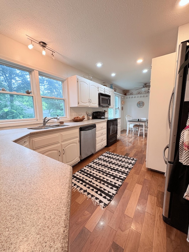 2412 S Camber Ave, Springfield, MO 65809 - kitchen featuring appliances with stainless steel finishes, light wood-type flooring, white cabinets, a textured ceiling, and light countertops