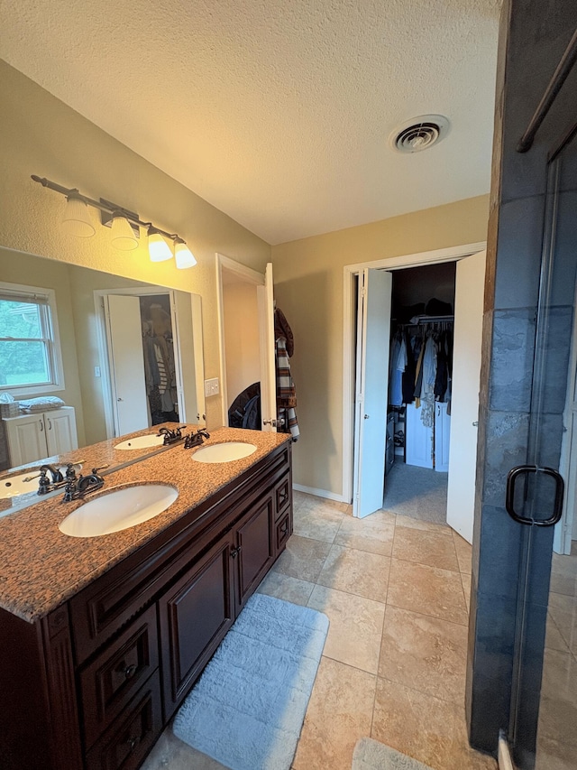 2412 S Camber Ave, Springfield, MO 65809 - bathroom with a spacious closet, double vanity, a textured ceiling, and a stall shower