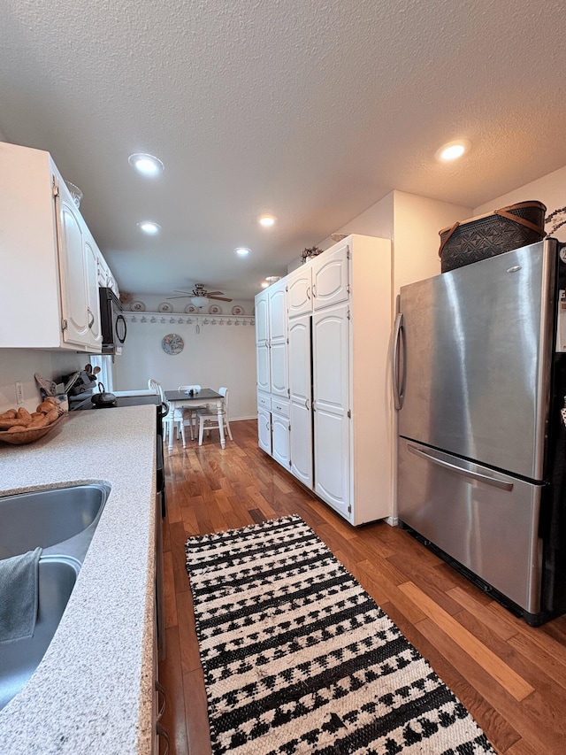 2412 S Camber Ave, Springfield, MO 65809 - kitchen featuring freestanding refrigerator, white cabinets, dark wood-style flooring, recessed lighting, and a textured ceiling