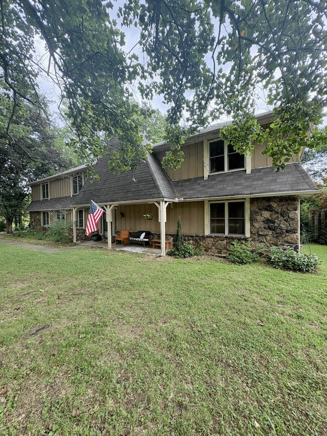 2412 S Camber Ave, Springfield, MO 65809 - view of front facade featuring stone siding, a front lawn, board and batten siding, a patio area, and a shingled roof