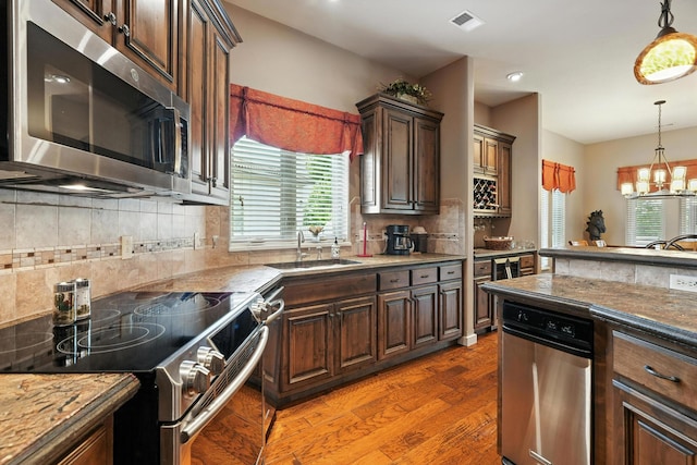 208 Siena Blvd, Branson, MO 65616 - kitchen with appliances with stainless steel finishes, light wood-style flooring, backsplash, pendant lighting, and a chandelier