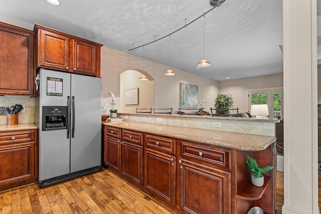 128 Mulligan Ct, Branson, MO 65616 - kitchen featuring stainless steel fridge with ice dispenser, a peninsula, light wood-style flooring, arched walkways, and tasteful backsplash
