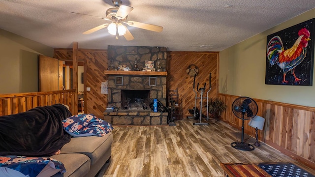 12 Riverbend Rd, Mammoth Spring, AR 72554 - living area with wooden walls, a textured ceiling, wood finished floors, a ceiling fan, and a fireplace