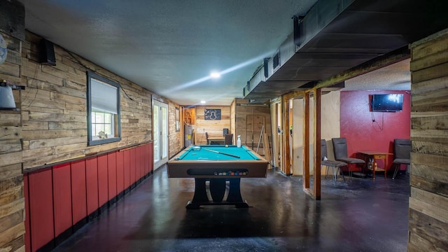 12 Riverbend Rd, Mammoth Spring, AR 72554 - playroom featuring finished concrete flooring, billiards table, wooden walls, water heater, and a textured ceiling