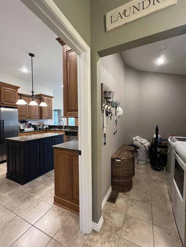 7876 County Road 3400, Mountain View, MO 65548 - kitchen with washer and clothes dryer, freestanding refrigerator, a center island, dark countertops, and decorative light fixtures