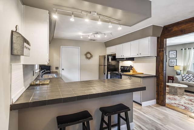 3430 S Elmview Ave, Springfield, MO 65804 - kitchen featuring freestanding refrigerator, a peninsula, tile countertops, black electric range oven, and under cabinet range hood