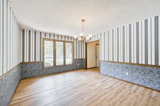 5751 S Kings Ave, Springfield, MO 65810 - unfurnished room featuring wallpapered walls, a chandelier, wood finished floors, and a textured ceiling