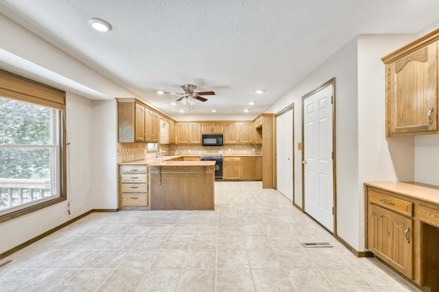 5751 S Kings Ave, Springfield, MO 65810 - kitchen featuring black microwave, stove, a peninsula, a ceiling fan, and tasteful backsplash