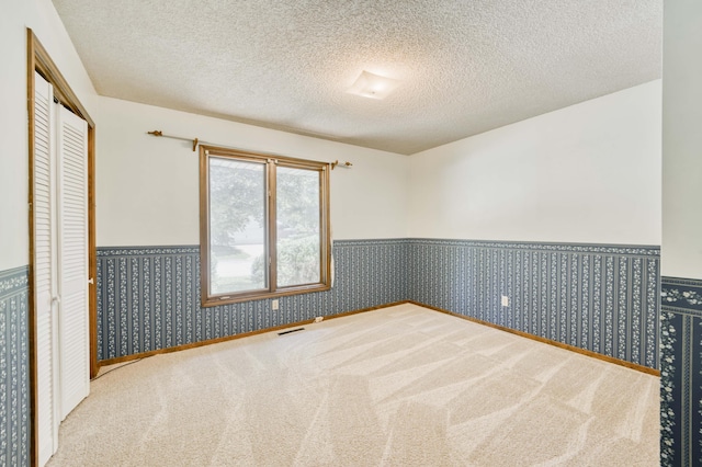 5751 S Kings Ave, Springfield, MO 65810 - unfurnished bedroom with wainscoting, carpet, a closet, and a textured ceiling