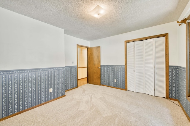 5751 S Kings Ave, Springfield, MO 65810 - unfurnished bedroom featuring a wainscoted wall, a textured ceiling, a closet, and carpet flooring