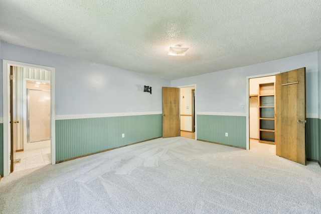5751 S Kings Ave, Springfield, MO 65810 - unfurnished bedroom featuring wainscoting, a spacious closet, carpet, a textured ceiling, and a closet