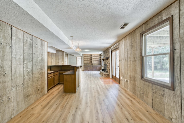 5751 S Kings Ave, Springfield, MO 65810 - kitchen featuring a textured ceiling, open floor plan, wood walls, plenty of natural light, and light wood finished floors