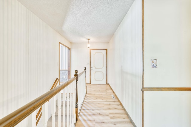 5751 S Kings Ave, Springfield, MO 65810 - corridor with light wood-style floors, a textured ceiling, and an upstairs landing