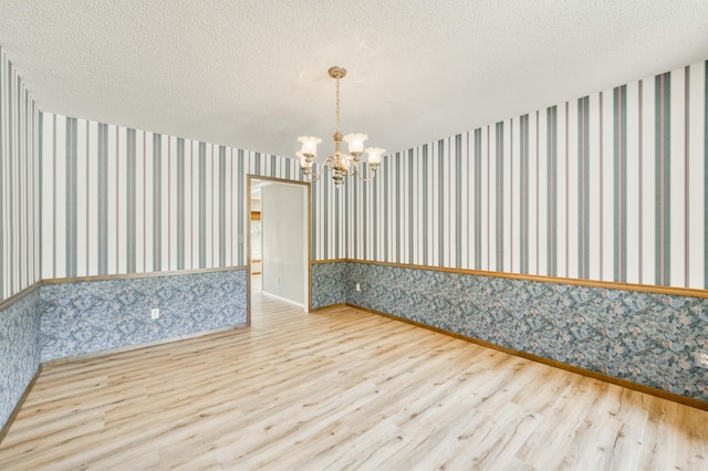 5751 S Kings Ave, Springfield, MO 65810 - unfurnished room with wood finished floors, a chandelier, wallpapered walls, and a textured ceiling