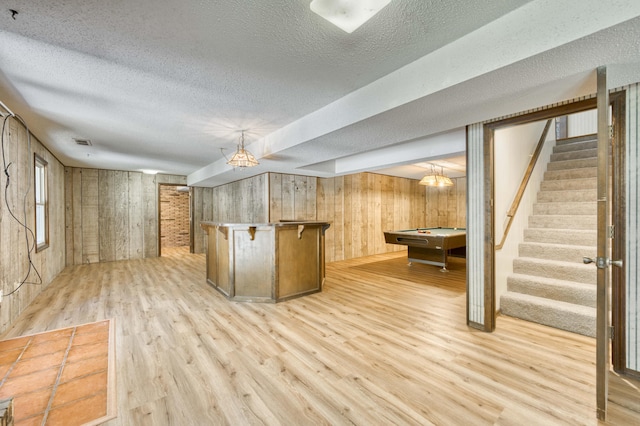 5751 S Kings Ave, Springfield, MO 65810 - basement with light wood-type flooring, a textured ceiling, stairs, bar area, and wooden walls