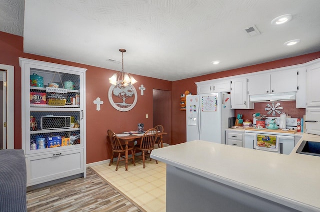 1360 Johnson Rd, Sparta, MO 65753 - kitchen featuring white appliances, under cabinet range hood, light countertops, light wood-style floors, and a chandelier