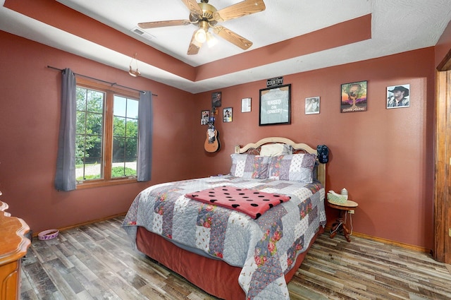 1360 Johnson Rd, Sparta, MO 65753 - bedroom featuring wood finished floors, a tray ceiling, and ceiling fan